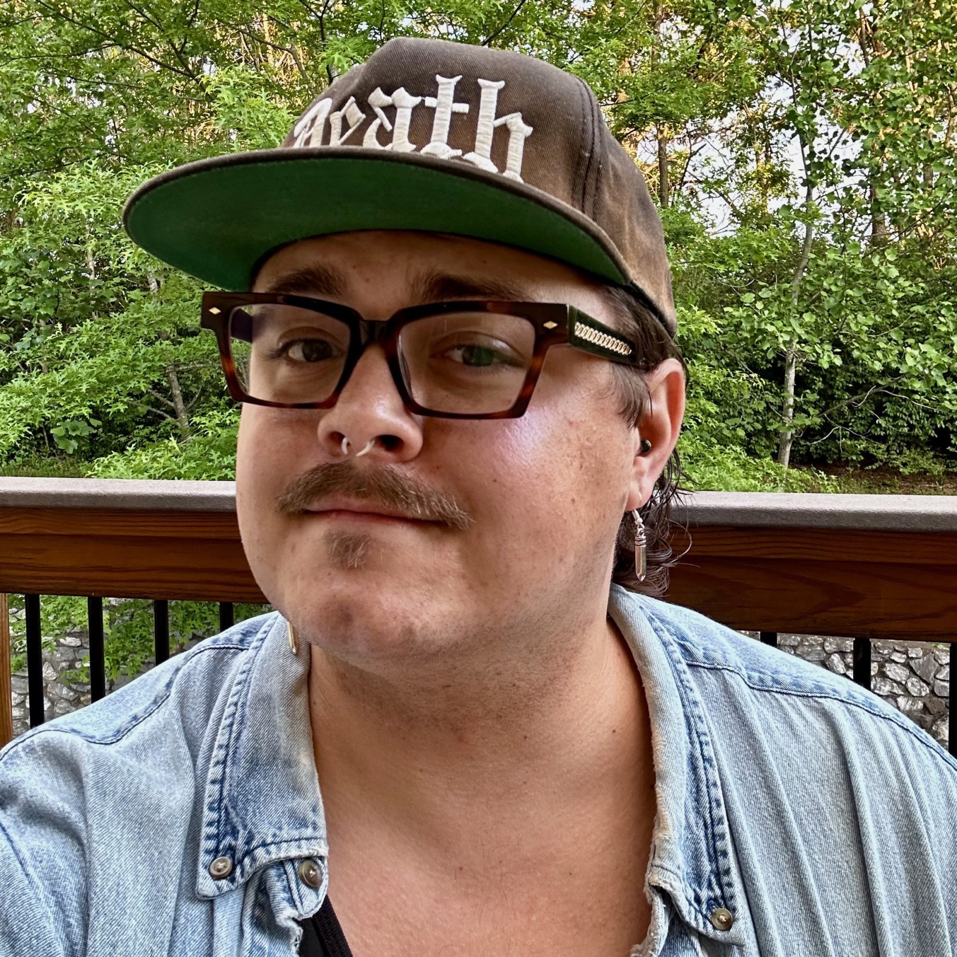 Bob looking at the camera wearing glasses and and hat that says death in heavy metal script.